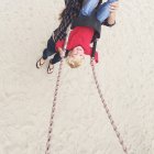 Mujer empujando a su hijo en swing - foto de stock