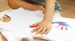 Boy hand printing on t-shirt — Stock Photo