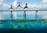 Garçons sautant dans la mer de la jetée — Photo de stock