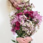 Ragazza che tiene grande mazzo di fiori rosa — Foto stock