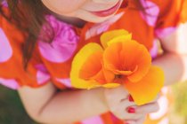 Девушка держит оранжевые цветы — стоковое фото