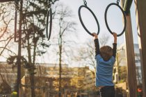 Boy hanging from rings — Stock Photo