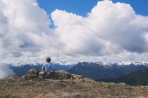 Хлопчик сидить на вершині гори — стокове фото