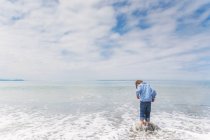 Ragazzo in piedi su roccia in mare — Foto stock