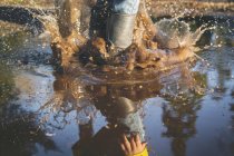 Child legs splashing in puddle — Stock Photo