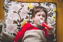 Boy on floor singing into toy microphone — Stock Photo