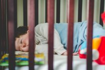 Boy sleeping in crib — Stock Photo