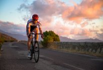 Чоловік їде на велосипеді на заході сонця — стокове фото
