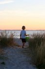 Мальчик идет на пляж с пластиковым ведром — стоковое фото