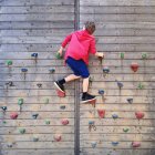 Junge klettert an Kletterwand — Stockfoto