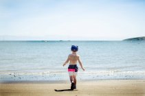 Boy on beach running towards sea — Stock Photo