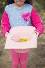 Girl holding hat with flowers — Stock Photo