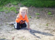 Мальчик сидит на земле — стоковое фото