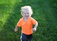 Sonriente chico corriendo al aire libre - foto de stock