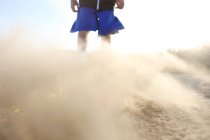Menino em shorts com areia soprando — Fotografia de Stock