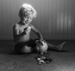 Menino brincando com porquinho banco — Fotografia de Stock