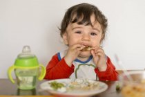 Niño sentado a la mesa comiendo - foto de stock