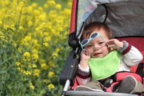 Criança sentado segurando óculos de sol — Fotografia de Stock