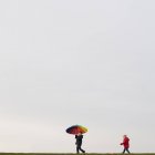 Jungen gehen mit Regenschirm — Stockfoto
