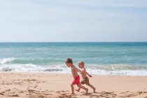 Deux garçons courent le long de la plage — Photo de stock