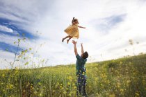 Отец бросает дочь в воздух — стоковое фото
