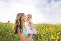 Mother kissing baby girl in field — Stock Photo