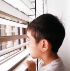 Хлопчик дивиться через вікно — стокове фото