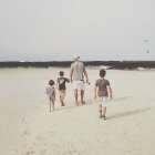 Mann mit Kindern spaziert am Strand — Stockfoto