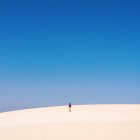 Man walking up sand dune — Stock Photo
