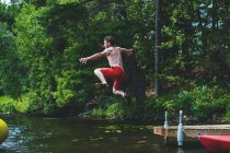 Man jumping off a jetty into lake — Stock Photo