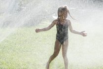 Menina jogando em aspersores de água — Fotografia de Stock