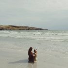 Donna in spiaggia con cane — Foto stock