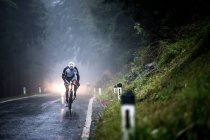 Uomo in bicicletta su una strada bagnata sotto la pioggia — Foto stock