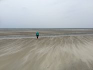 Donna anziana in piedi sulla spiaggia — Foto stock