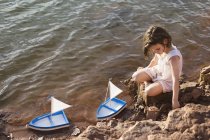 Menina sentada em rochas junto ao lago — Fotografia de Stock