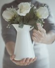 Hombre sosteniendo jarra de flores - foto de stock