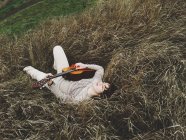 Niño acostado hierba con guitarra - foto de stock