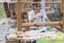 Mujer joven tejiendo telar - foto de stock