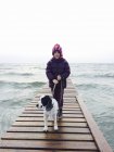 Дівчина і собака стоять на пірсі — стокове фото