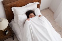Teenager-Mädchen versteckt sich unter Bettdecke — Stockfoto