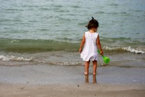 Baby girl standing on beach — Stock Photo