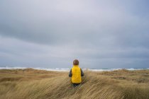Мальчик идет по траве к океану — стоковое фото
