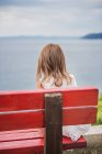 Девушка, сидящая на скамейке с видом на море — стоковое фото