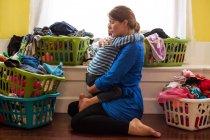 Madre con figlio circondata da cestini della lavanderia — Foto stock