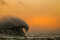 Barrel Wave crashing over reef at sunset — Stock Photo
