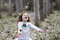 Chica lanzando hojas de otoño - foto de stock