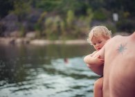Pai carregando seu filho pelo lago — Fotografia de Stock