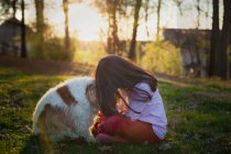 Mädchen sitzt mit Hund im Garten — Stockfoto