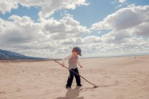Хлопчик пише в піску з палицею — стокове фото