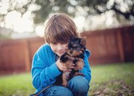 Niño abrazando yorkie cachorro perro - foto de stock